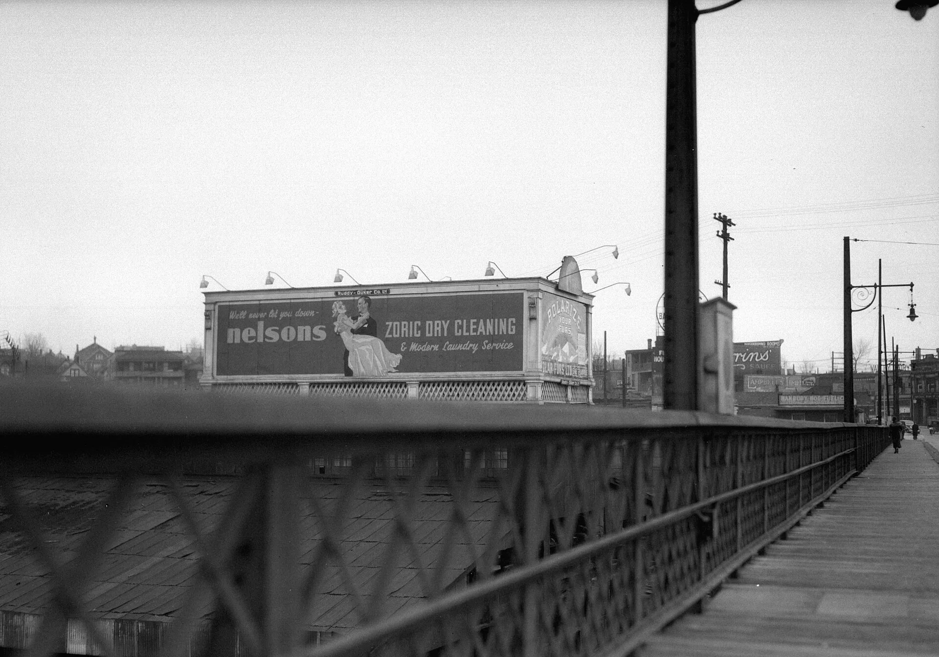 Lighted Ruddy-Duker Ltd. billboard advertising Nelsons Zoric Dry Cleaning and Modern Laundry Service on the west side of the Granville Bridge Vancouver .