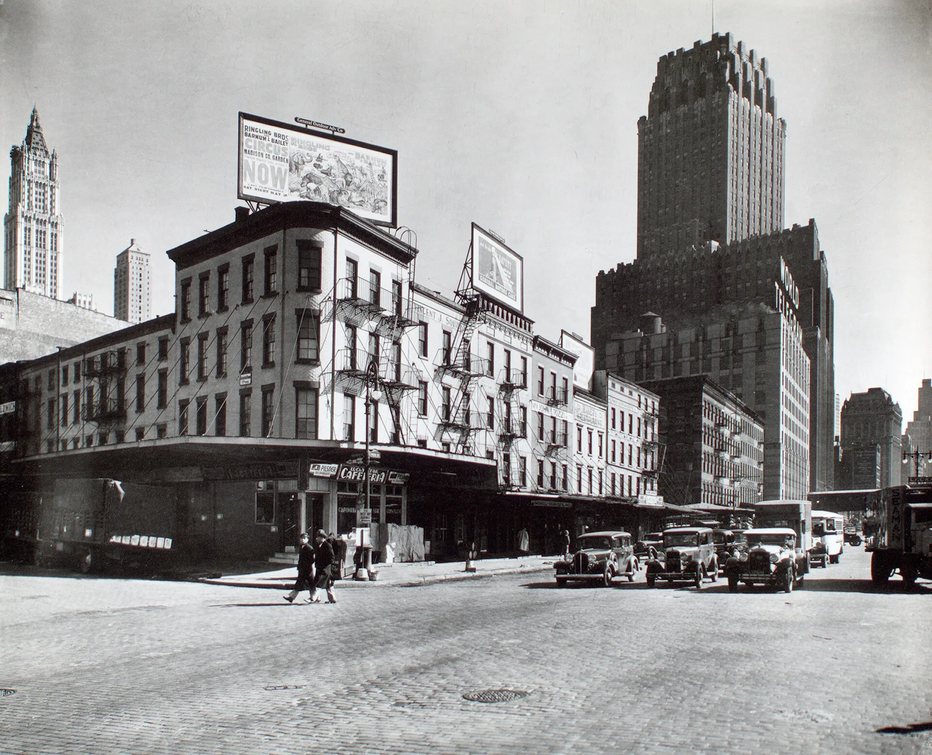 * Code: III.B.1. Billboards top buildings at the corner of Warren and West Sts., cars stopped in street, Telephone and World Telegram building beyond at r. Citation/Reference: CNY# 99