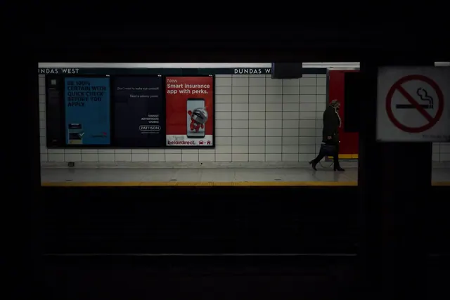 A lone commuter walks past billboards in Toronto's Dundas West subway station.
